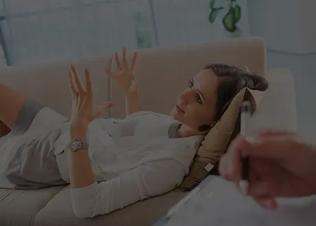 A woman sitting on the couch with her hands up.